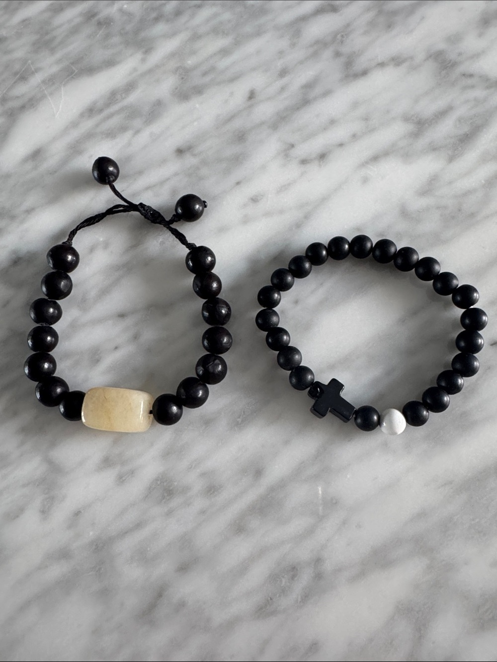 Set of 2 black bed bracelets. 1 w/ large rectangular quartz bead, 1 w/ cross
